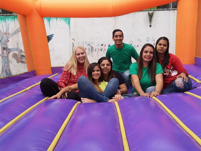 Síx people are sitting on an inflatable trampoline and smiling.