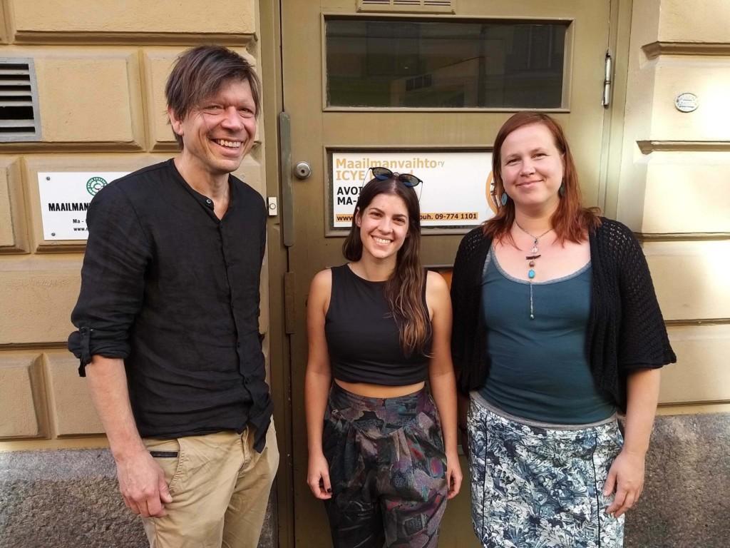 Kuvassa kolme henkilöä seisoo Maailmanvaihdon oven edessä. Vasemmalla Mauri Pajunen, keskellä Marta Melendez Ortega, oikealla Mari Takalo.