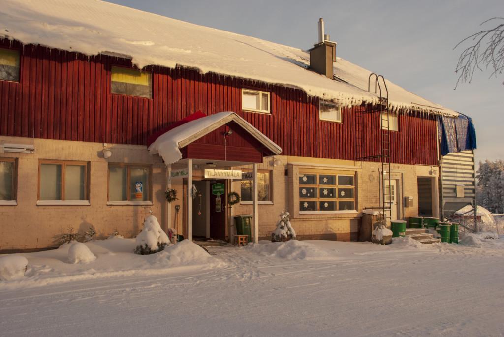 A building on a snowy day, on top of the front door it says in Finnish "a farm store".