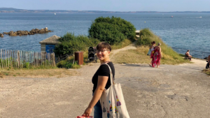 A person standing near the sea and looking at the camera