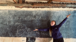 A person standing in front of a blackboard that says "we love MD Laura Maria so much. Bye MD Laura