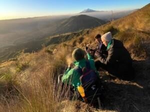 Three people sitting in a mountaneo