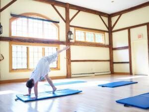A person doing gymnastic movements on a gym mat indoors.